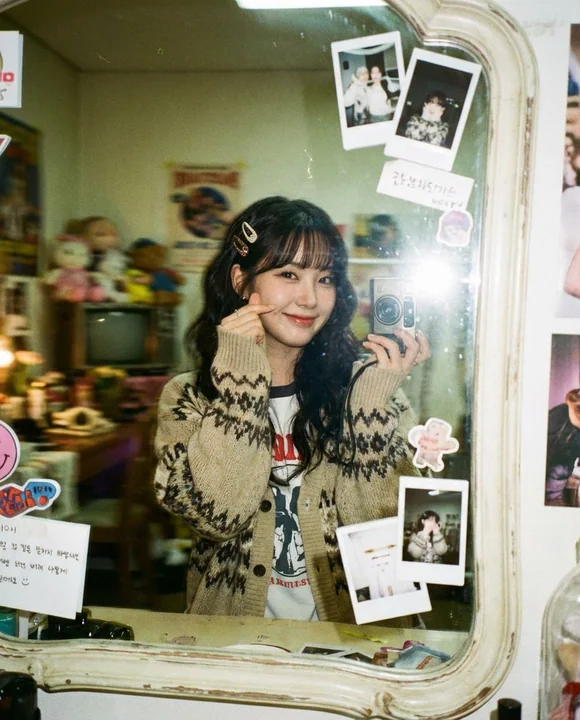 Sweet girl film portrait posing with heart gesture in front of mirror