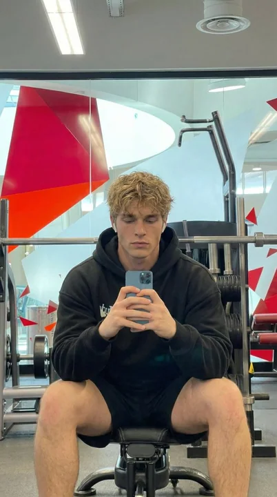 Blond fitness guy in front of the gym mirror