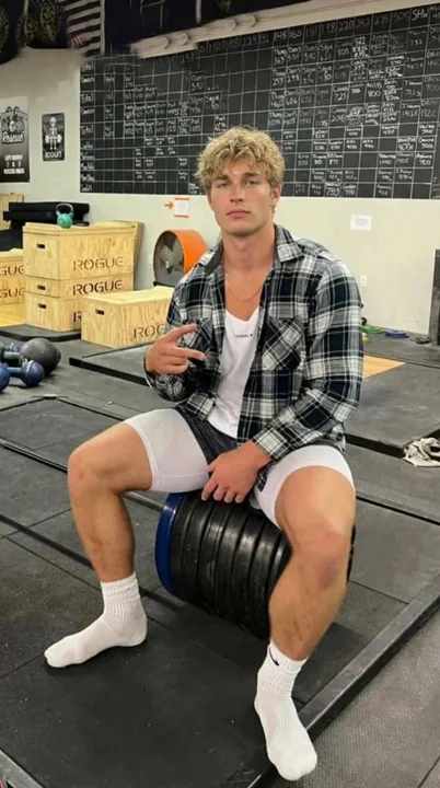 Blond fitness guy sitting on a barbell plate