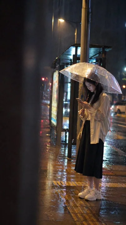 Jeune fille attendant le bus à la gare de bus sous la pluie