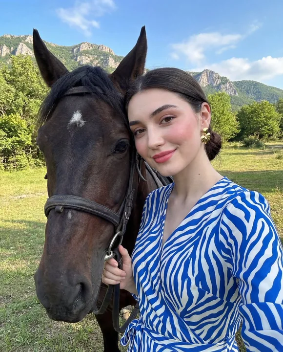 Fashion portrait of a person and a horse against a mountainous background in sunlight