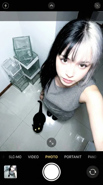 A youthful girl interacting with a black cat from a low-angle perspective