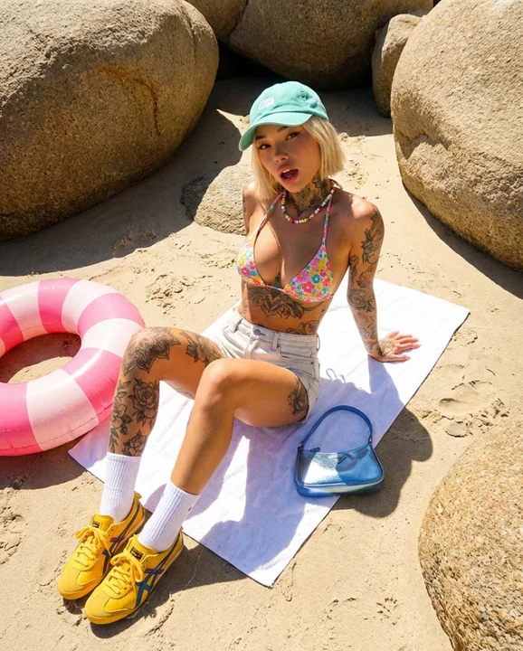 Une fille élégante avec des tatouages, portant des chaussures de sport, parmi des rochers ensoleillés