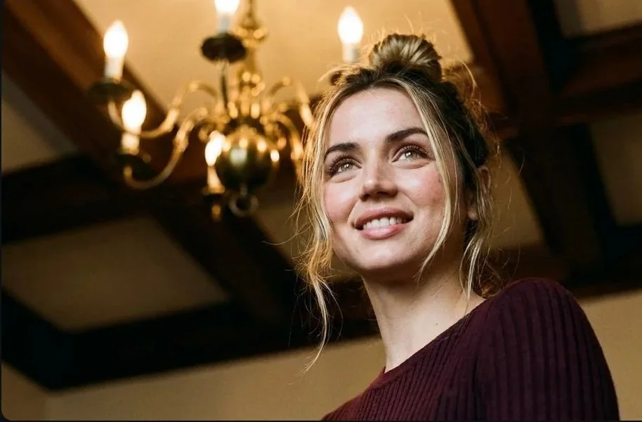 Portrait d’une beauté absolue en contre-plongée à très faible angle sous la lumière chaude d’un lustre vintage